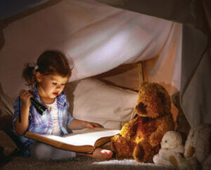 pg 16 Child reading with flashlight in fort